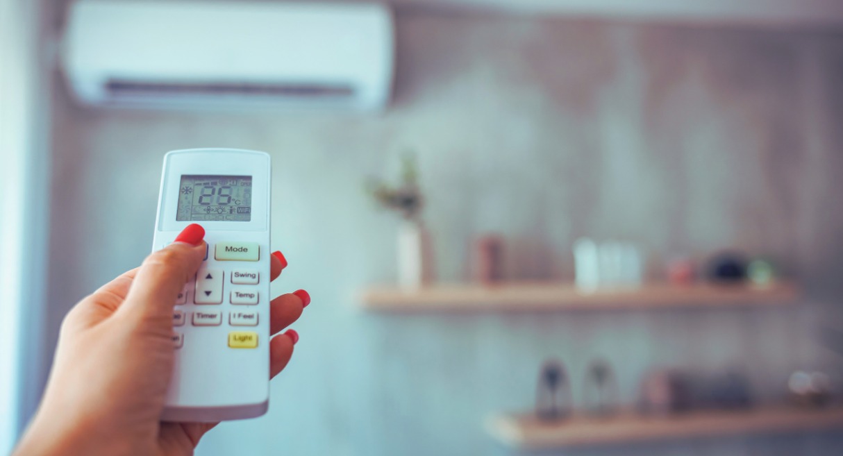 Main réglant la température sur la télécommande d'un climatiseur mural