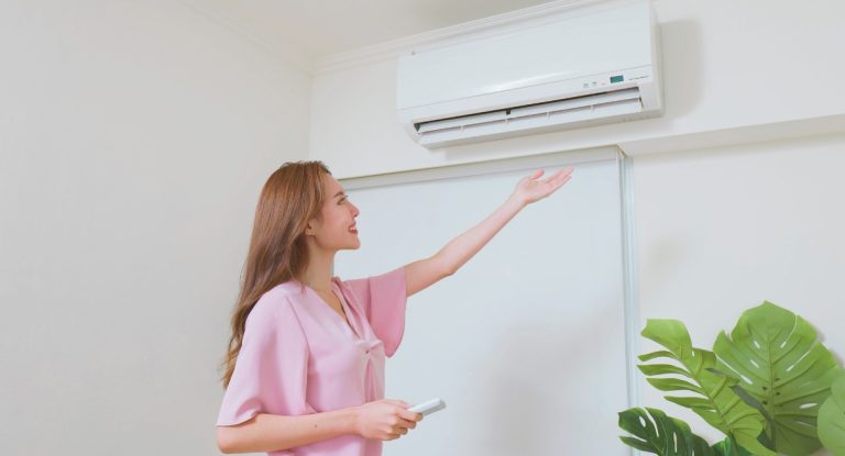 Femme vérifiant le flux d'air d'un climatiseur mural