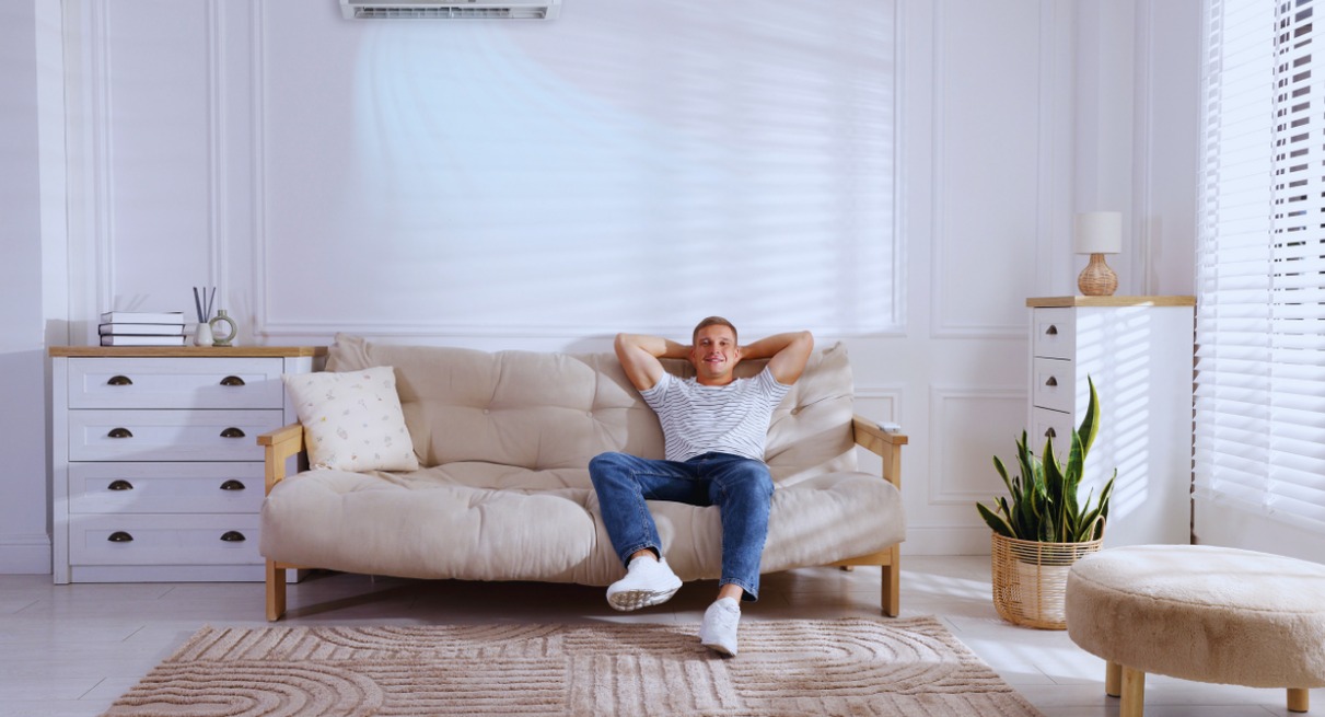 Homme détendu sur un canapé sous un climatiseur mural dans un salon