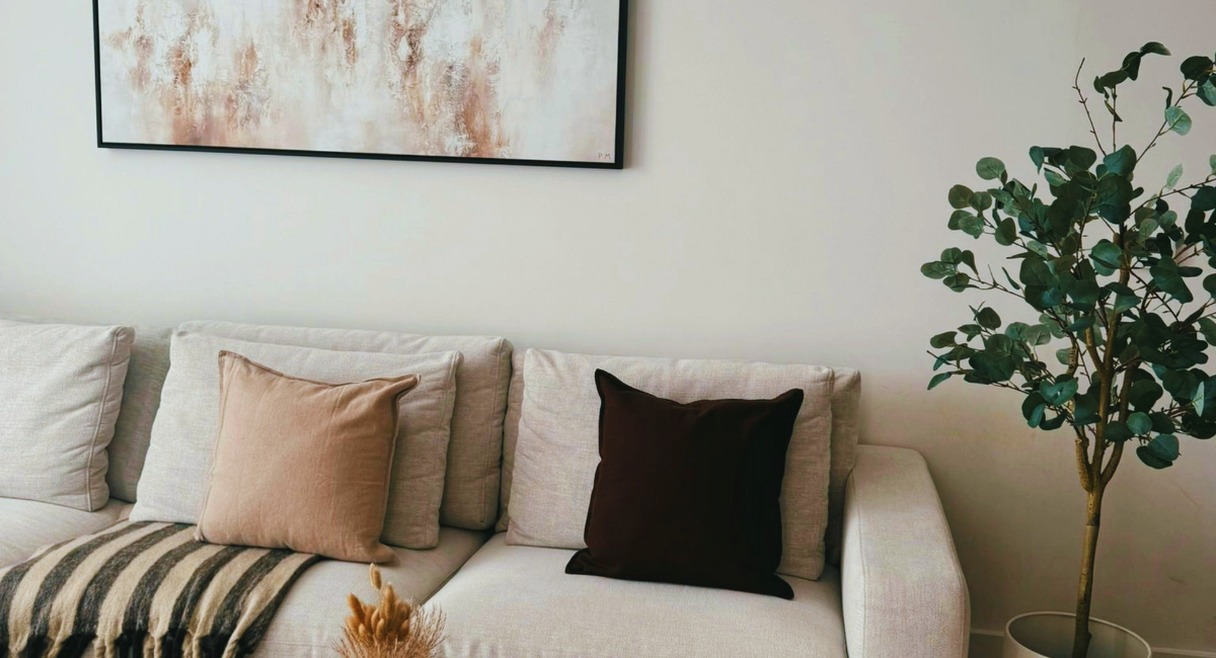 Canapé cosy dans un salon chaleureux avec coussins et plante verte