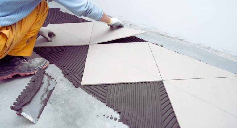 Artisan posant du carrelage sur une chape de béton