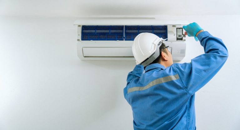 Technicien en combinaison entretenant un climatiseur mural
